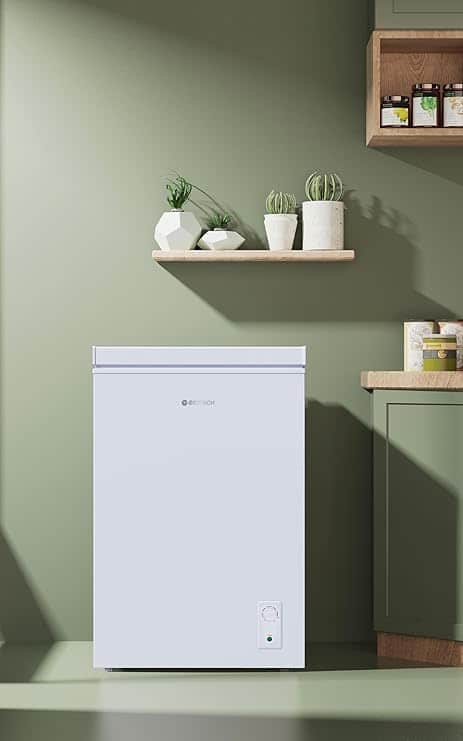 Congélateur coffre CEDTECH 99L installé dans une cuisine au design moderne, avec des étagères décorées de plantes et d’épices.