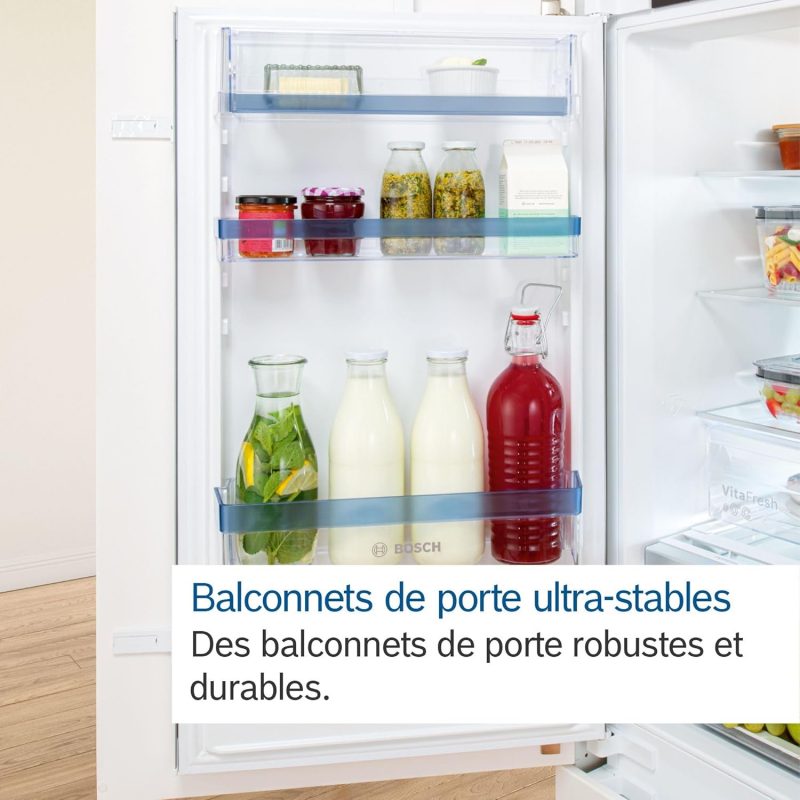 Vue de l’intérieur de la porte d’un réfrigérateur, montrant des balconnets robustes contenant des bouteilles de lait, de jus et divers condiments. 
